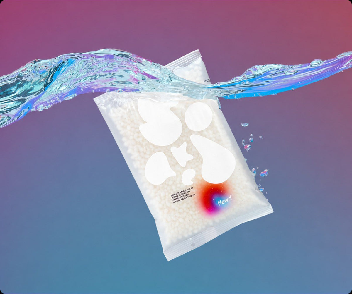 Flewd fragrance-free Ache Erasing magnesium bath soak clear pouch splashing into water on a purple and blue background