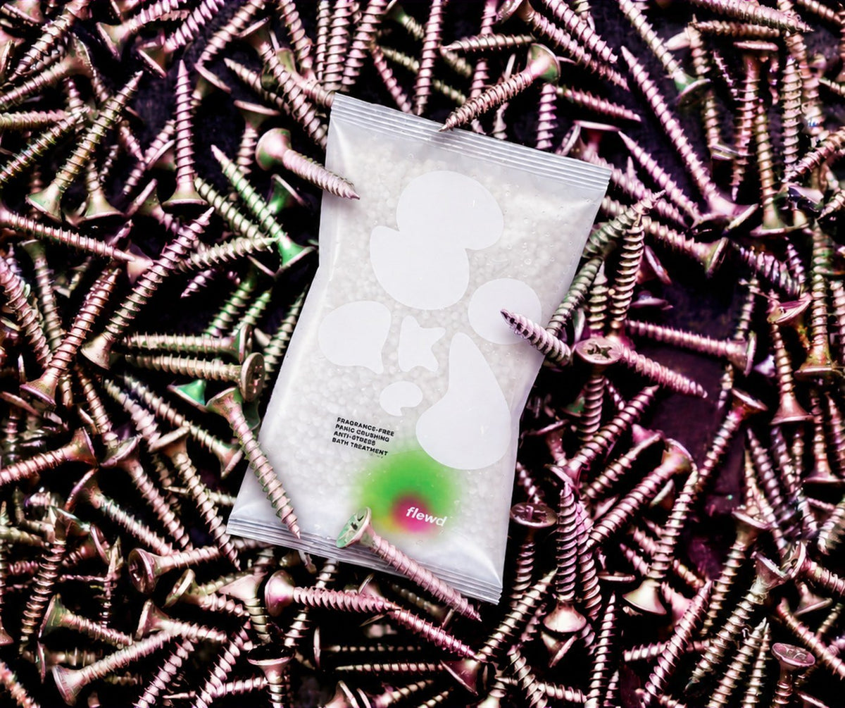 Flewd fragrance-free Panic Crushing stresscare bath soak clear pouch on a pile of metal screws